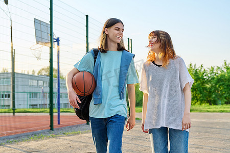 篮球场附近带球在户外行走的年轻男女学生