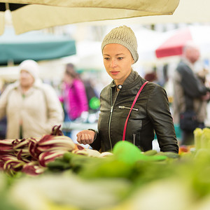 妇女在当地食品市场购买蔬菜。