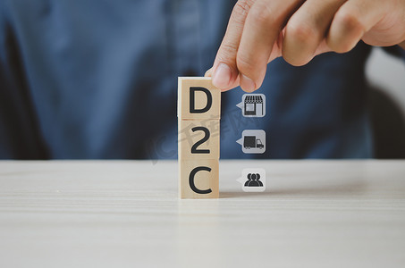 手工将木制立方体与直接面向消费者的 D2C 和图标放在桌子和复制空间上。商业概念。