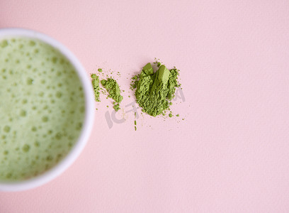 绿茶粉摄影照片_日本磨碎的绿茶粉近模糊的白色陶瓷碗，带有搅打过的抗氧化健康抹茶拿铁和泡沫