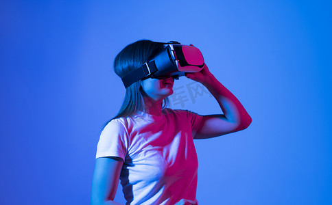 黑发女人在元宇宙中戴着 VR 护目镜耳机探索或玩虚拟增强现实。