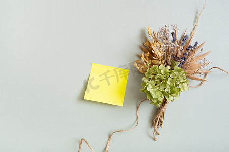 装饰干花摄影照片_用于笔记的空白彩色纸和彩色背景上的一束干花和香草
