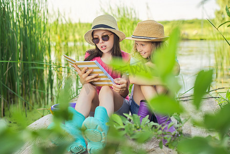两个女孩在大自然中休息玩耍、阅读笔记本的孩子们