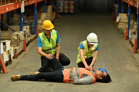 仓库工人昏迷不醒地躺在水泥地上，同事们帮助受伤者进行急救