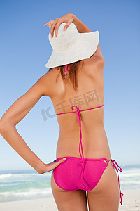 一个穿着沙滩装的迷人青少年握着她的肩膀的后视图