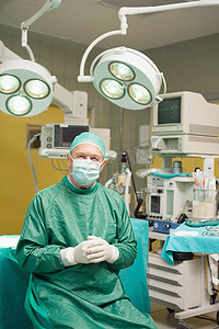 双手合十摄影照片_微笑的外科医生坐着，双手合十
