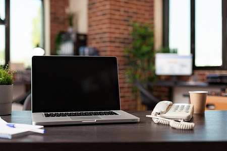 空荡荡的商务空间中配有笔记本电脑和固定电话的办公桌
