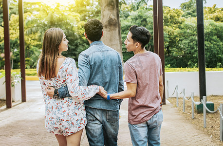 不忠的女孩和男友在公园散步，牵着另一个男人的手。