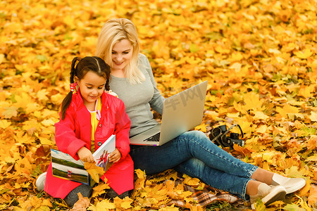 都市妇女和女儿在公园里带着笔记本电脑。
