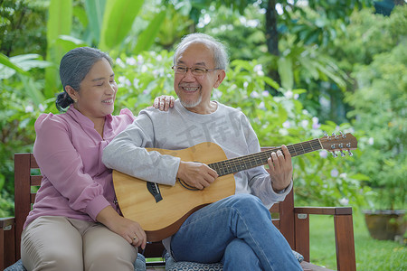 亚洲老年夫妇老人弹吉他，而他的妻子一起唱歌