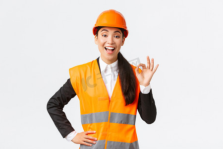满意的快乐亚洲女工程师、戴着安全帽和反光夹克的施工经理表现出良好的姿态很高兴，保证建筑质量，确保一切都出色