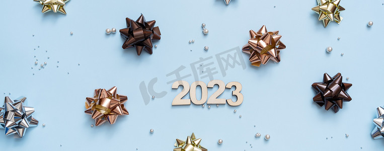 数字倒计时创意摄影照片_横幅与数字 2023 在明亮的节日背景与弓和珠顶视图。