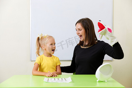 言语治疗摄影照片_言语治疗师在办公室训练发音时与小女孩一起工作