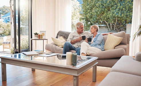 放松、退休和喝咖啡，与老年夫妇坐在沙发上，一起在客厅里享受宁静的早晨。