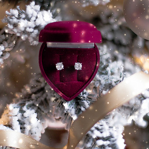 圣诞树上心形珠宝礼盒中的钻石耳环、除夕夜、情人节和寒假的爱情礼物