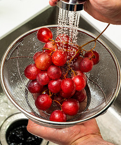 用过滤器在流水下清洗红葡萄的特写