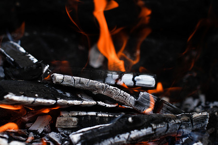 燃烧的木头，火焰仍在燃烧，营火或烤架的深石背景