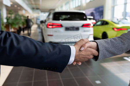汽车经销店的买卖双方在买车后握手