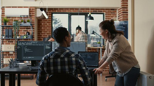 两个软件开发人员在办公桌前做高五手势，多个屏幕运行 ai 代码