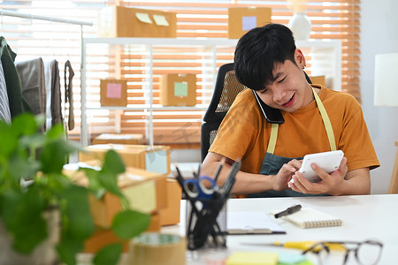 快乐的亚洲男子小企业主通过智能手机确认订单或接受客户订单。