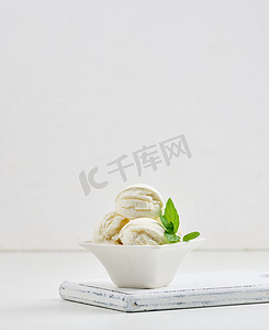 白色陶瓷盘中带绿薄荷叶的香草冰淇淋球