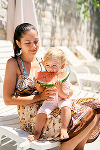 吃女孩西瓜摄影照片_小女孩坐在妈妈怀里吃一块西瓜