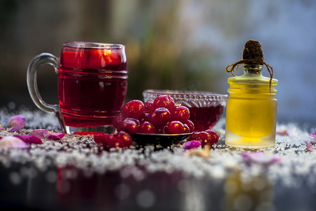 果浆摄影照片_新鲜甜樱桃或李属鸟的特写镜头，其油、果汁和茶在黑色光泽的表面上，配有生新鲜樱桃。