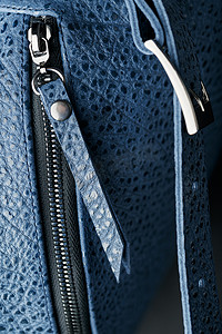 锁扣特写，深色背景上真皮制成的蓝色背包的元素，手工制作。