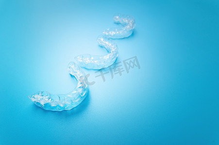 特写，新的透明牙套在蓝色背景上排成一排。