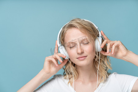 年轻女子闭眼通过耳机听音乐的特写肖像