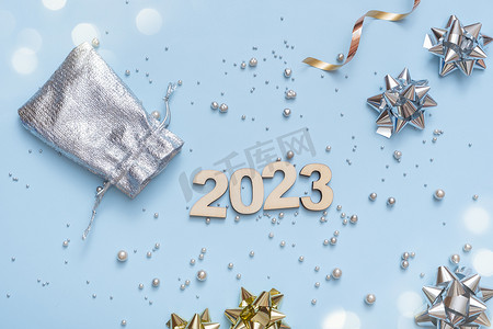 数字倒计时创意摄影照片_数字 2023 在明亮的节日背景与弓和珠顶视图。