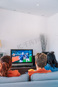 朋友们在客厅里看电视上的足球比赛。