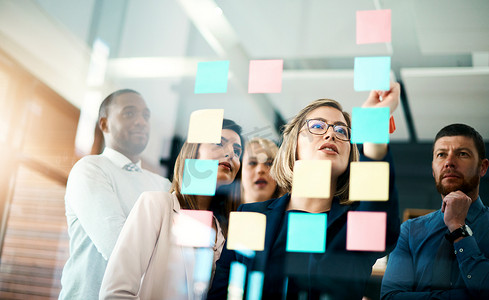 创意团队或业务团队在玻璃墙上贴上便利贴进行创新规划。
