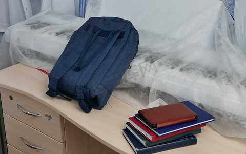 蓝色的学校背包和课本，学生桌上的笔记本。