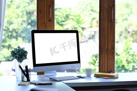 在创意工作场所的白色桌子上放置有空白屏幕和办公用品的样机。