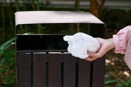 妇女用手将空塑料袋扔进垃圾箱或垃圾箱