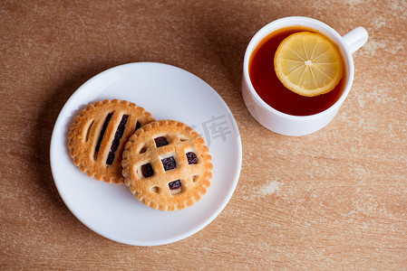 一桌点心摄影照片_一杯茶和柠檬，桌面上碟子里放着果酱的饼干