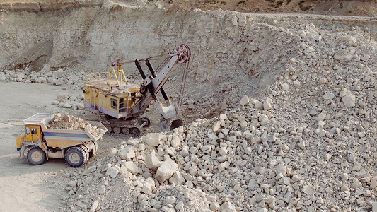 矿用挖掘机摄影照片_挖掘机将土壤装载到矿用自卸卡车中。