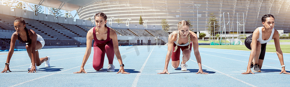 一群坚定的女运动员在体育场的运动跑道上开始冲刺或跑步比赛。