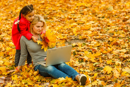 都市妇女和女儿在公园里带着笔记本电脑。