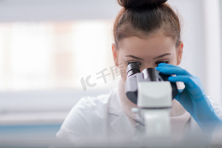 透过显微镜看的女学生科学家