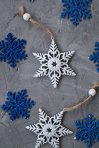 圣诞树上的两个白色装饰品以雪花和许多蓝色雪花的形式躺在灰色的混凝土背景上。