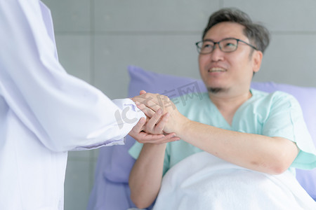 医生护理摄影照片_微笑着感恩的病人握着医生的手感谢帮助支持护理。