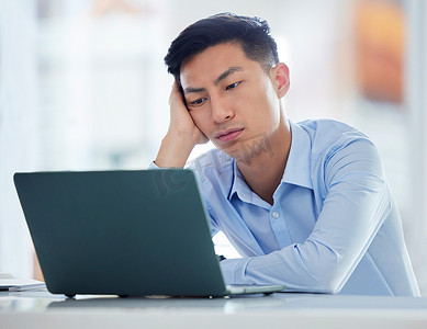 一位年轻的亚洲商人在等待缓慢的笔记本电脑连接错误时看起来无聊、疲倦和沮丧。