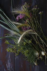 新鲜的洋葱、莳萝花、黑麦小穗和深蓝色桌子上的亚罗粉红色花朵，夏季概念。