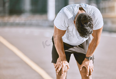 疲惫的男子在健身跑步后休息，从有氧训练中休息一下，并在城市的道路上进行健康锻炼。