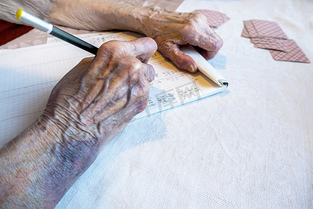 一位有瘀伤的老妇人的手在纸牌游戏中写下分数