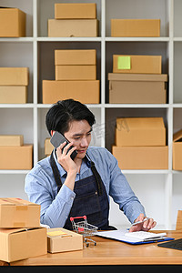 确认订单摄影照片_年轻男性小企业主通过手机通话确认客户订单。