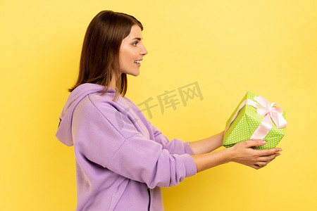 微笑的年轻成年女性拿出绿色包装的礼盒，送礼物，祝贺。