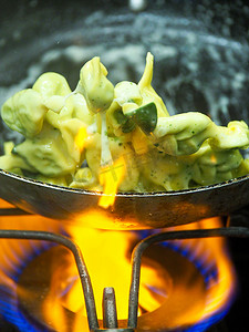 厨师在锅里炒混合黄油鼠尾草意大利饺子意大利面食